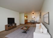 Thumbnail 5 of 26 - Fargo, ND Monticello. A living room with a couch a coffee table and a tv. The dining room in the background with a four chair table and a fan above it.