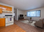 Thumbnail 3 of 15 - Fargo, ND Morningside Apartments. A living room with a couch, tv, and a coffee table. A long window brightens the room with natural light.