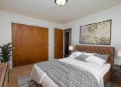 Thumbnail 4 of 16 - a bedroom with a large bed and a painting on the wall. Fargo, ND North Manor Apartments