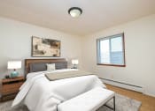 Thumbnail 6 of 16 - a bedroom with a white bed and a white couch. Fargo, ND North Manor Apartments