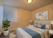 Thumbnail 6 of 28 - a bedroom with a large bed and a potted plant. Fargo, ND Pacific Park 2 Apartments.