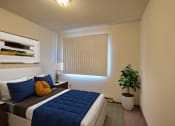Thumbnail 4 of 18 - a bedroom with a large bed and a potted plant. Fargo, ND Pacific South Apartments