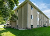 Thumbnail 20 of 20 - a brick building with green grass and a tree. Fargo, ND Park Circle Apartments.