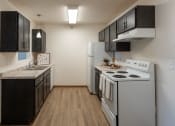 Thumbnail 6 of 16 - Fargo, ND Parkside Apartments. A kitchen with white appliances and black cabinets