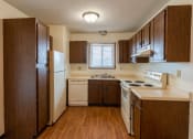 Thumbnail 6 of 23 - Kitchen with wooden cabinets and white appliances with a small widow above the sink at Parkwest Gardens West Fargo, ND 58078