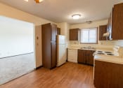 Thumbnail 5 of 23 - Kitchen with white appliances and brown cabinets a small window above the sink brightens the room with natural light at Parkwest Gardens West Fargo, ND