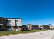Thumbnail 23 of 23 - Apartment buildings on a street with a blue sky in the background at Parkwest Gardens West Fargo