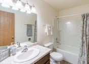 Thumbnail 17 of 19 - Fargo, ND Patricia Ann Apartments. A bathroom with a white bathtub and a white toilet next to a sink with a mirror