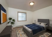 Thumbnail 6 of 15 - A bedroom with a bed and a dresser and a window. Fargo, ND Pinehurst Apartments.