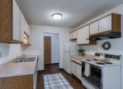 Thumbnail 20 of 36 - an empty kitchen with white appliances and wooden cabinets. Fargo, ND Place One Apartments
