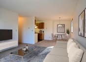 Thumbnail 4 of 36 - A living room with a couch, coffee table, tv, and a dining room in the background. Fargo, ND Place One Apartments.