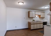 Thumbnail 12 of 36 - an empty kitchen with white walls and wood flooring and a sink and a counter. Fargo, ND Place One Apartments