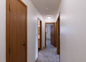 Thumbnail 17 of 36 - a hallway with wooden doors and closets and a carpeted floor. Fargo, ND Place One Apartments