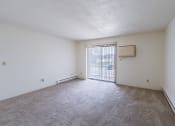 Thumbnail 7 of 36 - an empty living room with a sliding glass door and carpeted floor. Fargo, ND Place One Apartments