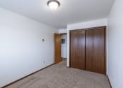 Thumbnail 10 of 14 - a bedroom with carpet and a door to a closet. Fargo, ND Plumtree Apartments