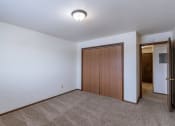 Thumbnail 8 of 14 - a room with a carpeted floor and a door to a hallway. Fargo, ND Plumtree Apartments