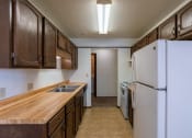 Thumbnail 6 of 14 - an empty kitchen with a refrigerator and a sink. Fargo, ND Plumtree Apartments