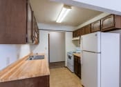 Thumbnail 7 of 14 - an empty kitchen with a refrigerator and a sink. Fargo, ND Plumtree Apartments