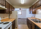 Thumbnail 5 of 14 - the view of a kitchen with a stove sink and refrigerator. Fargo, ND Plumtree Apartments