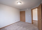Thumbnail 27 of 32 - a bedroom with a door to a closet and a carpeted floor. Fargo, ND  Prairie Park Apartments