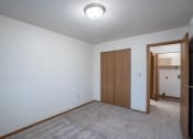 Thumbnail 18 of 32 - a bedroom with carpet and a door to a closet. Fargo, ND  Prairie Park Apartments