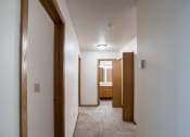 Thumbnail 19 of 32 - a hallway with a carpeted floor and wooden doors to a bathroom. Fargo, ND  Prairie Park Apartments