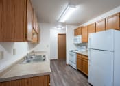 Thumbnail 14 of 32 - a kitchen with white appliances and wood cabinets. Fargo, ND  Prairie Park Apartments