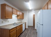 Thumbnail 15 of 32 - a kitchen with white appliances and wooden cabinets and a refrigerator. Fargo, ND  Prairie Park Apartments