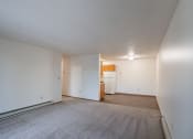 Thumbnail 13 of 32 - the living room and kitchen of an apartment with white walls and carpet. Fargo, ND  Prairie Park Apartments