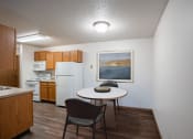 Thumbnail 4 of 32 - a kitchen and dining area with a table and chairs and a refrigerator. Fargo, ND Prairie Park Apartments