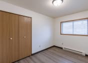 Thumbnail 15 of 21 - an empty bedroom with a closet and a window. Fargo, ND Prairiewood Courts Apartments