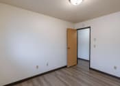 Thumbnail 16 of 21 - the living room of an empty apartment with a door to the hallway. Fargo, ND Prairiewood Courts Apartments
