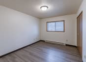 Thumbnail 17 of 21 - a bedroom with wooden floors and a window. Fargo, ND Prairiewood Courts Apartments