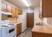 Thumbnail 13 of 21 - a kitchen with white appliances and wooden cabinets. Fargo, ND Prairiewood Courts Apartments