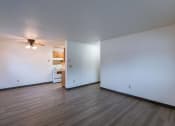 Thumbnail 11 of 21 - the living room and kitchen of an empty apartment with white walls and wood floors. Fargo, ND Prairiewood Courts Apartments