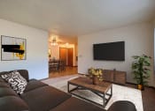 Thumbnail 3 of 21 - Fargo, ND Prairiewood Courts Apartments.  A living room with a couch, coffee table, and a tv. the dining room is in the background.
