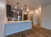 Thumbnail 11 of 26 - a kitchen and living room with a large island and wood flooring