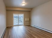 Thumbnail 12 of 26 - an empty living room with wood flooring and a door to a balcony. Fargo, ND Prairiewood Meadows