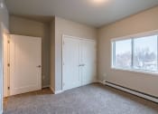 Thumbnail 19 of 26 - an empty bedroom with two doors and a window. Fargo, ND Prairiewood Meadows Apartments