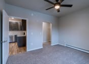 Thumbnail 21 of 26 - a bedroom with a ceiling fan and a kitchen. Fargo, ND Prairiewood Meadows Apartments