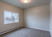 Thumbnail 18 of 26 - an empty room with carpet and a window. Fargo, ND Prairiewood Meadows Apartments