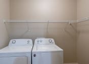 Thumbnail 23 of 26 - an empty laundry room with two washes and a dryer.Fargo, ND Prairiewood Meadows Apartments