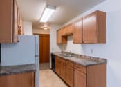 Thumbnail 5 of 10 - a kitchen with wood cabinets and granite counter tops and a refrigerator. Fargo, ND Schrock Apartments