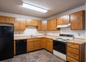 Thumbnail 17 of 25 - an empty kitchen with wooden cabinets and black appliances. Fargo, ND Southview Village Apartments