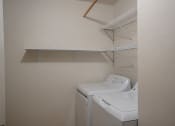 Thumbnail 14 of 25 - a washer and dryer in a laundry room with a shelf on the wall. Fargo, ND Southview Village Apartments