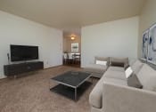 Thumbnail 2 of 10 - a living room with a couch, coffee table, and tv with the dining room in the background. Fargo, ND Southwind Apartment