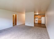 Thumbnail 6 of 14 - the living room and kitchen of an apartment with white walls and carpet. Fargo, ND Spring Apartments