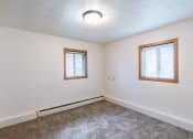 Thumbnail 10 of 14 - a bedroom of a house with carpet and two windows. Fargo, ND Spring Apartments
