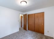 Thumbnail 11 of 14 - a bedroom with white walls and wooden doors and a ceiling light. Fargo, ND Spring Apartments