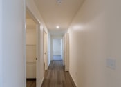 Thumbnail 38 of 43 - an empty hallway with white walls and wood flooring and a door to a closet. Fargo, ND Stonebridge Apartments
